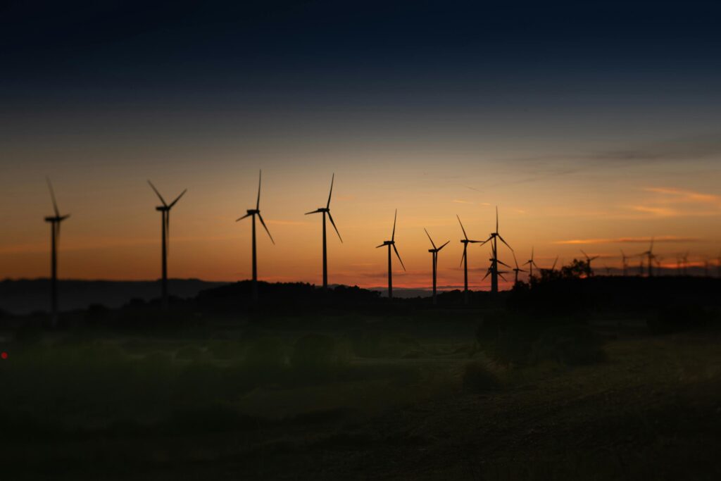 Silhouettes of wind turbines against a vibrant sunset in Lleida, Spain.